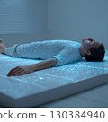 Man lying on a futuristic surface, glowing lines and dots forming a network pattern on his body, illustrating technological connectivity and data flow 130384940