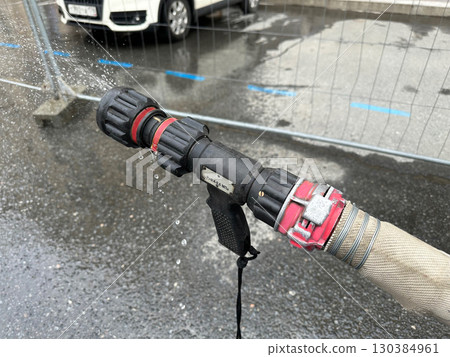 A fire hose is being used to spray water on a car. 130384961