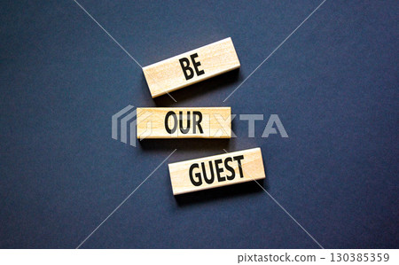 Be our guest symbol. Concept words Be our guest on beautiful wooden block. Beautiful black table black background. Business and be our guest concept. Copy space. 130385359