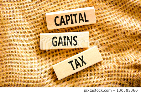 Capital gains tax symbol. Concept words Capital gains tax on beautiful wooden block. Beautiful canvas table canvas background. Business and capital gains tax concept. Copy space. 130385360