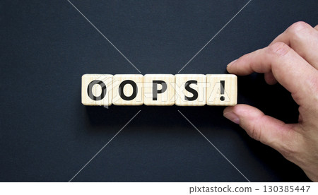 Oops symbol. Concept word Oops on beautiful wooden blocks. Beautiful black table black background. Businessman hand. Business lifestyle oops concept. Copy space. Oops symbol. Concept word Oops on beautiful wooden blocks. Beautiful black table black background. Businessman hand. Business lifestyle oops concept. Copy space. 130385447