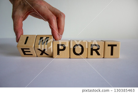 Hand is turning a cubes and changes the word 'import' to 'export'. Beautiful white background. Business concept. Copy space. 130385463