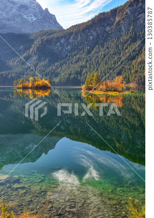 Amazing autumn landscape of islands with pine-trees in the middle of Eibsee lake. Amazing autumn landscape of islands with pine-trees in the middle of Eibsee lake. 130385787