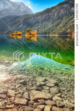 Stunning autumn landscape of Eibsee Lake in front of Zugspitze summit under sunlight. 130385789