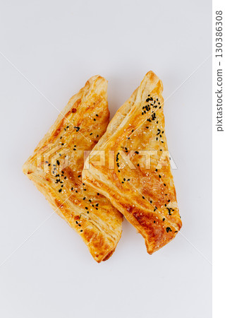 Golden puff pastry triangles with sesame seeds isolated on white background Golden puff pastry triangles with sesame seeds isolated on white background 130386308