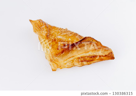Golden puff pastry triangles with sesame seeds isolated on white background 130386315