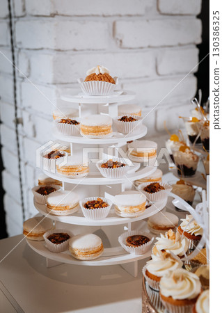 Luxury candy bar with cupcakes, macarons, and desserts on elegant golden trays 130386325