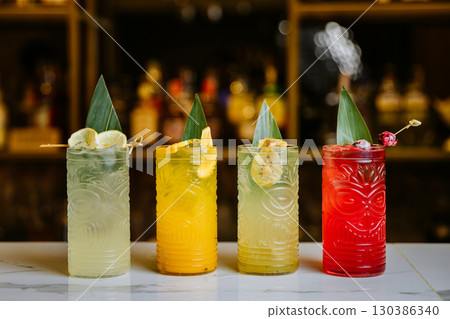 Colorful tiki cocktails with tropical garnishes on bar counter, vibrant and refreshing Colorful tiki cocktails with tropical garnishes on bar counter, vibrant and refreshing 130386340
