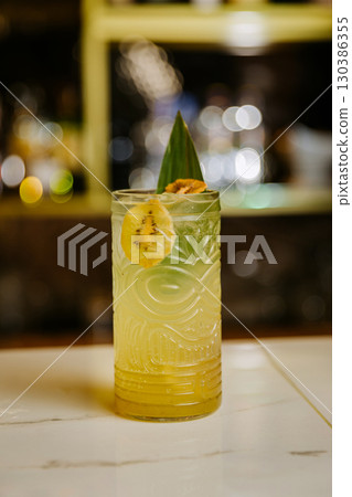 Tropical kiwi cocktail in tiki glass with garnish at bar counter, vibrant and refreshing Tropical kiwi cocktail in tiki glass with garnish at bar counter, vibrant and refreshing 130386355
