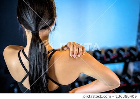 Back view of a cool woman exercising at the gym, touching her shoulder, upper body, muscle training girl Back view of a cool woman exercising at the gym, touching her shoulder, upper body, muscle training girl 130386409