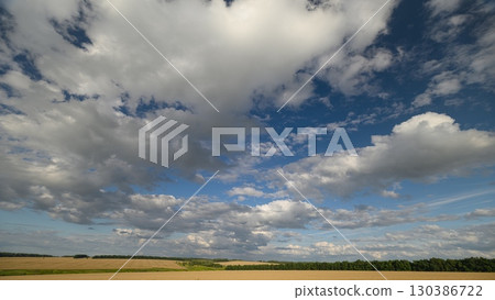 A Beautiful, Expansive Sky with Fluffy, Billowing Clouds Over Lush Open Fields of Greenery 130386722