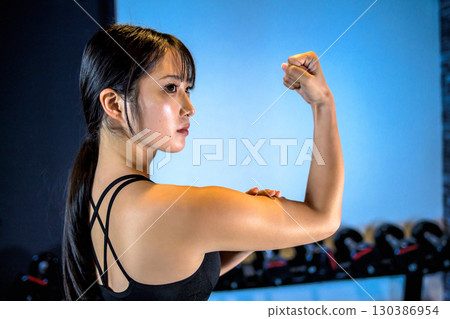 一個酷女人在健身房鍛鍊的後視圖，二頭肌，上身，肌肉訓練女孩 130386954