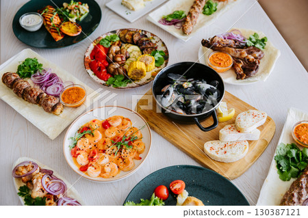 Top view of assorted grilled meats, seafood, and side dishes on a restaurant table Top view of assorted grilled meats, seafood, and side dishes on a restaurant table 130387121