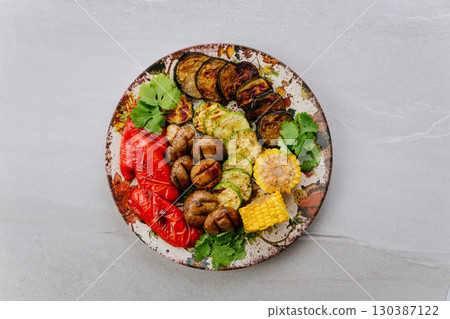 Grilled vegetables with herbs on ceramic plate. Colorful healthy vegan meal top view 130387122