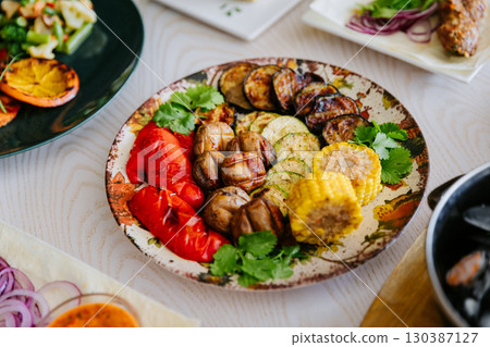 Grilled vegetables with herbs on ceramic plate. Colorful healthy vegan meal top view 130387127