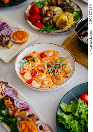 Shrimp in creamy spicy sauce with cherry tomatoes and herbs in ceramic bowl Shrimp in creamy spicy sauce with cherry tomatoes and herbs in ceramic bowl 130387129