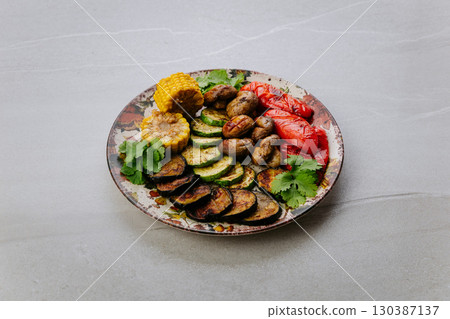Grilled vegetables with herbs on ceramic plate. Colorful healthy vegan meal top view Grilled vegetables with herbs on ceramic plate. Colorful healthy vegan meal top view 130387137