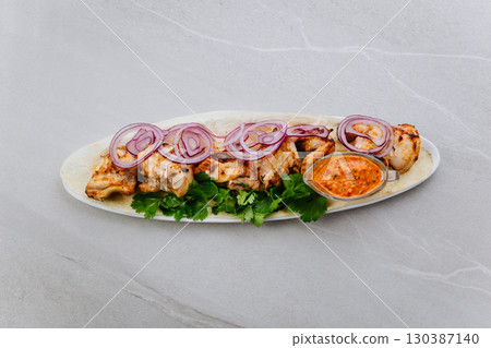 Grilled chicken with red onion, fresh herbs and spicy sauce on lavash bread 130387140