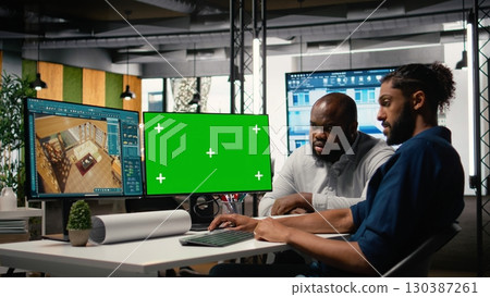 Real estate colleagues evaluates blueprints next to chroma key screen, zoning regulations and property investment opportunity for housing and residential area market growth. 130387261