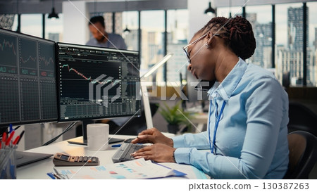 Equity analyst in office reviews quarterly earnings paperwork to assess future stock market value, talking on phone. Trader making calls, conducting financial analysis to improve investments Equity analyst in office reviews quarterly earnings paperwork to assess future stock market value, talking on phone. Trader making calls, conducting financial analysis to improve investments 130387263