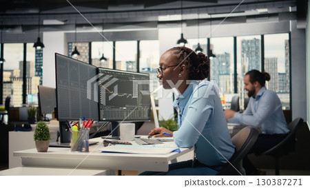 Day trader analyzes stock market price charts, taking notes to make informed buy and sell decisions. Stockbroker writing down analysis insights, placing orders using trading platform Day trader analyzes stock market price charts, taking notes to make informed buy and sell decisions. Stockbroker writing down analysis insights, placing orders using trading platform 130387271