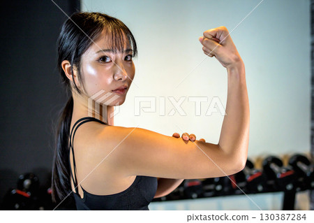 Back view of a cool woman exercising at the gym, bicep, upper body, muscle training girl Back view of a cool woman exercising at the gym, bicep, upper body, muscle training girl 130387284