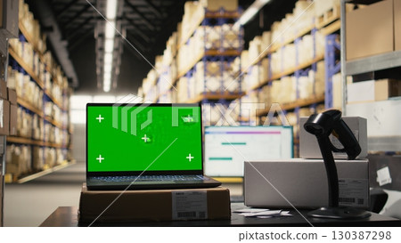 Modern warehouse facility featuring isolated workstation with chroma key display, surrounded by racks and delivery tools for e-commerce, order fulfillment and cargo boxes movement. Modern warehouse facility featuring isolated workstation with chroma key display, surrounded by racks and delivery tools for e-commerce, order fulfillment and cargo boxes movement. 130387298
