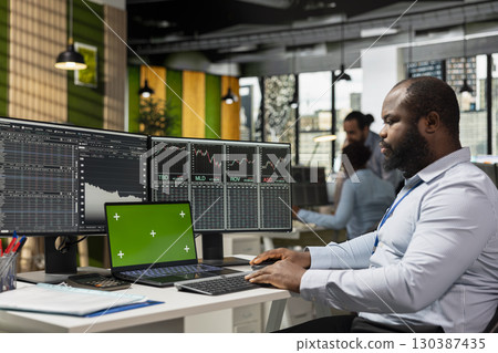Day trader in office using isolated screen laptop device to capitalize on stock market fluctuations. Prop firm employee analyzing price movements on chroma key notebook for fast profit opportunities 130387435