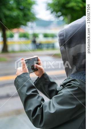 Child filming video with smartphone held horizontally in Bergen park. 130387504