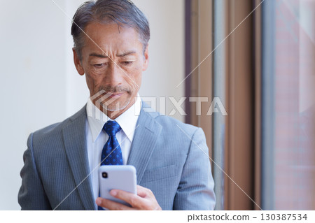 使用智慧型手機的資深商人 使用智慧型手機的資深商人 130387534