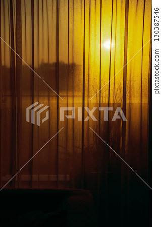 Golden sunset light shining through sheer curtains and foggy window indoors Golden sunset light shining through sheer curtains and foggy window indoors 130387546