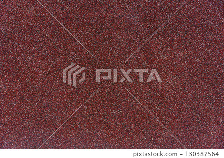 Close-up texture of red granular roofing surface with mineral coating for waterproofing, durability Close-up texture of red granular roofing surface with mineral coating for waterproofing, durability 130387564