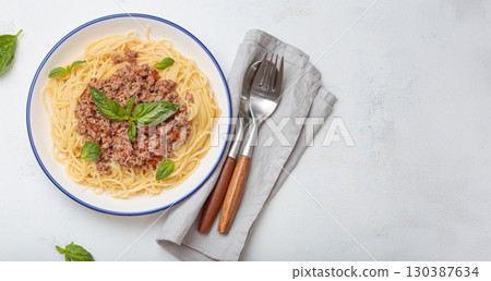 Italian spaghetti bolognese with basil and parmesan on plate on white background top view, space for text 130387634