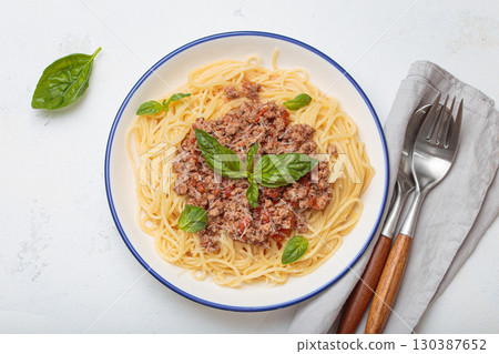 Italian spaghetti bolognese with basil and parmesan on plate on white background top view Italian spaghetti bolognese with basil and parmesan on plate on white background top view 130387652