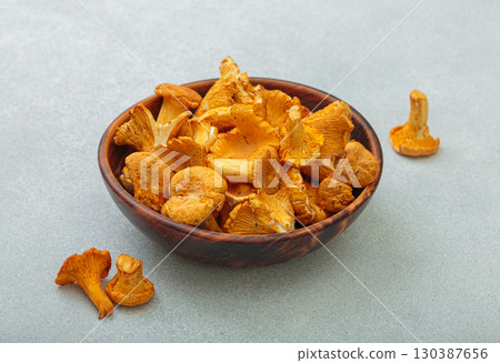 Fresh chanterelle mushrooms in a a rustic bowl on gray background table top view Fresh chanterelle mushrooms in a a rustic bowl on gray background table top view 130387656