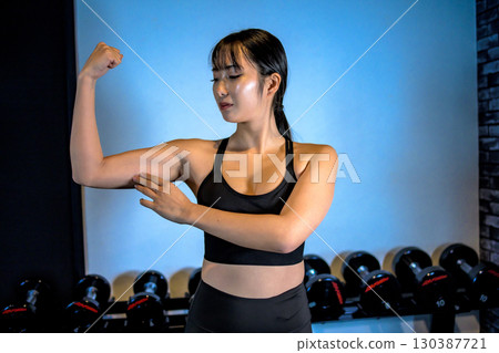 Woman touching her upper arm, cool woman exercising at the gym, biceps, upper body, muscle training girl Woman touching her upper arm, cool woman exercising at the gym, biceps, upper body, muscle training girl 130387721