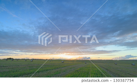 A breathtaking stunning sunset casting vibrant colors over a picturesque scenic field scene 130387754