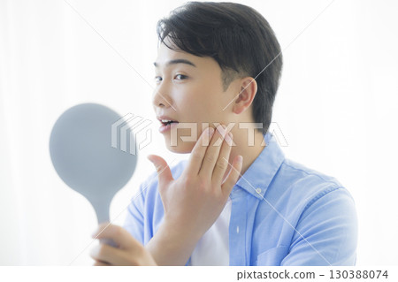 Man looking in a hand mirror 130388074