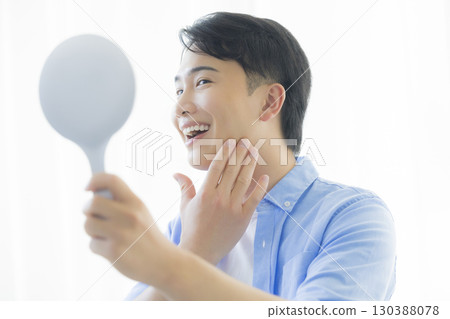 Man looking in a hand mirror Man looking in a hand mirror 130388078