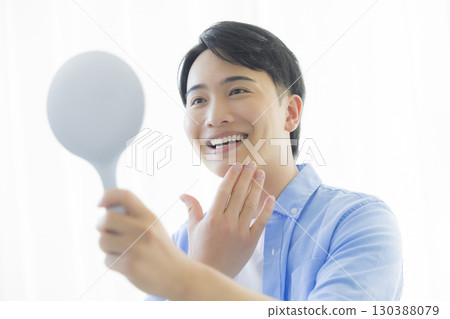 Man looking in a hand mirror 130388079