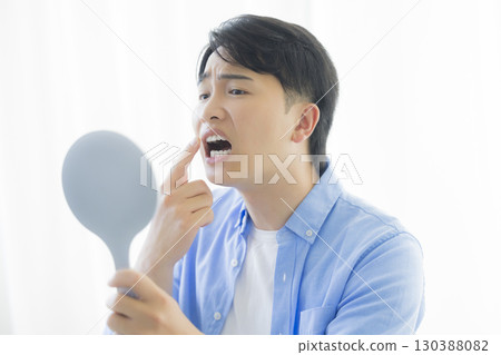 Man looking in a hand mirror Man looking in a hand mirror 130388082