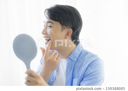 Man looking in a hand mirror Man looking in a hand mirror 130388085