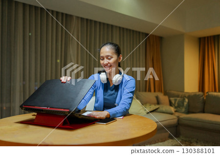 Woman Working from Home with Laptop and Headphones in Cozy Living Room Woman Working from Home with Laptop and Headphones in Cozy Living Room 130388101
