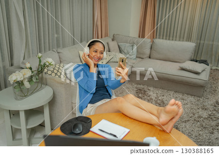 A Cheerful Woman Enjoying a Relaxing Virtual Chat from the Comfort of Home 130388165