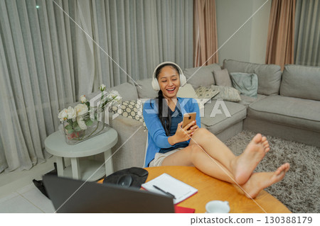 Young Woman Enjoying Leisure Time at Home with Headphones and Smartphone Young Woman Enjoying Leisure Time at Home with Headphones and Smartphone 130388179