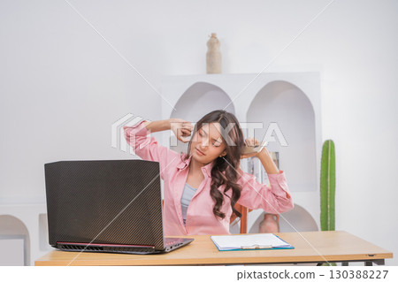A Young Woman Engaged in Stretching at Her Desk in a Modern and Stylish Workspace A Young Woman Engaged in Stretching at Her Desk in a Modern and Stylish Workspace 130388227