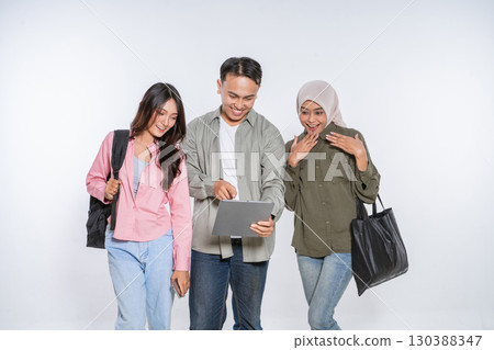 Young friends collaborating on a tablet in a creative studio, brainstorming ideas 130388347