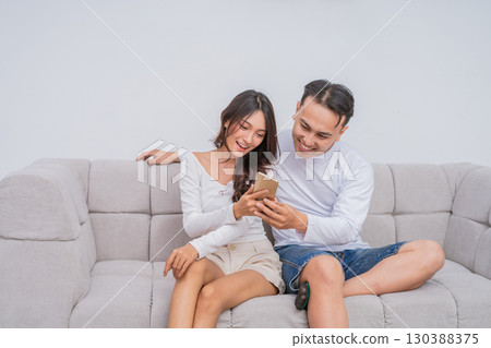 A Joyful Couple Enjoying Quality Time Together on the Couch While Using a Smartphone A Joyful Couple Enjoying Quality Time Together on the Couch While Using a Smartphone 130388375