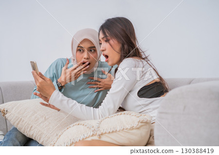Surprised Friends Excitedly Reacting to Exciting News on a Phone Call Together 130388419
