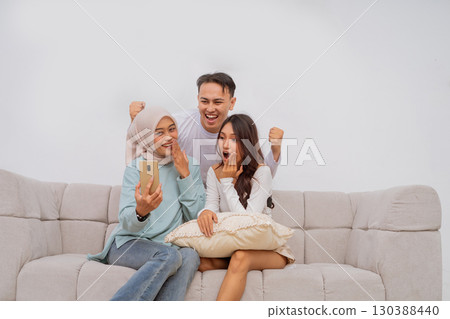 A group of happy friends taking a fun selfie while lounging on a couch 130388440